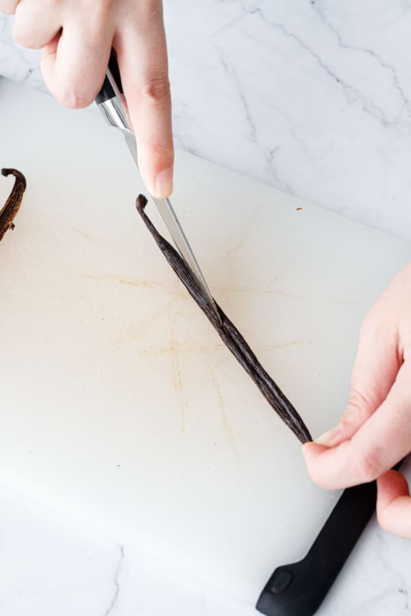 Splitting a vanilla bean down the middle with a small paring knife.