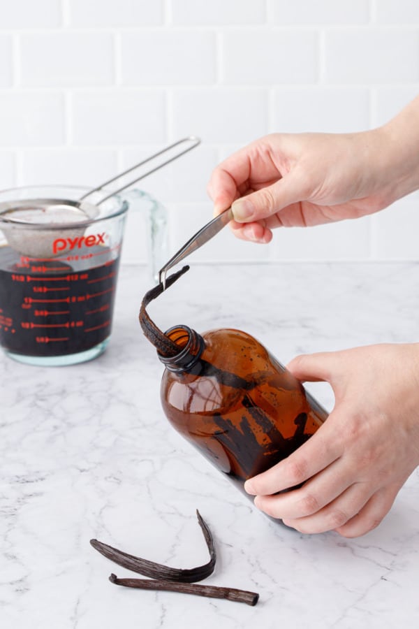 Using long tweezers to get the vanilla beans out of the glass bottle.