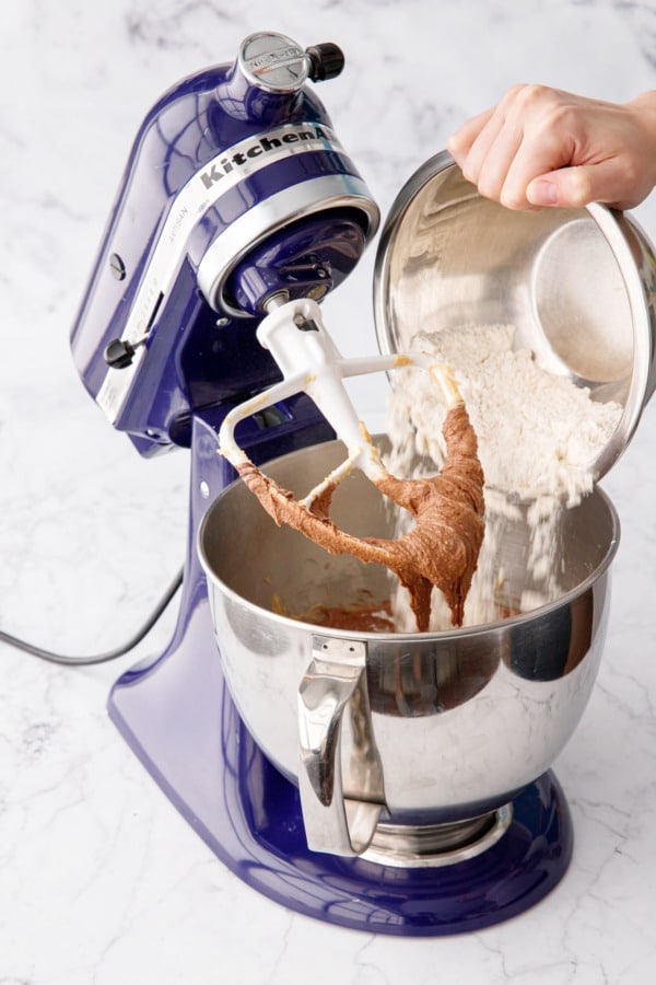 Pouring dry ingredients (flour, salt, baking soda) into mixing bowl with the now brown-colored dough.