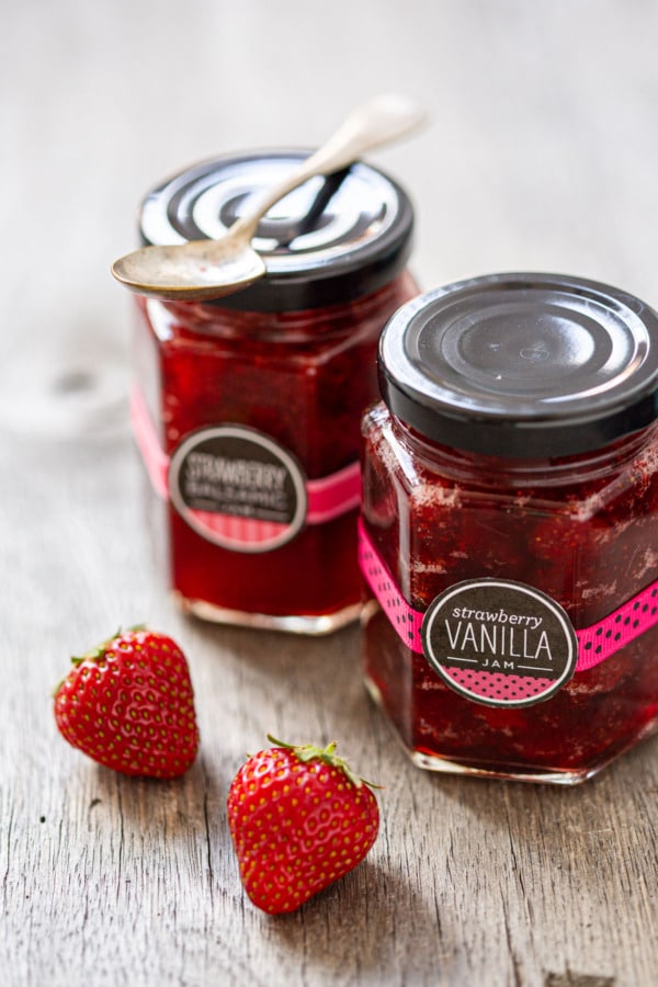 Jars of Strawberry Vanilla and Strawberry Balsamic Jam on a rustic wood background.