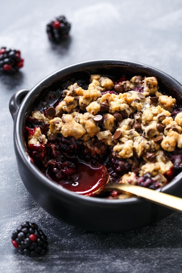 Spoon in a dish of Blackberry Chocolate Chip Cookie Crumble, showing the juicy purple berry filling