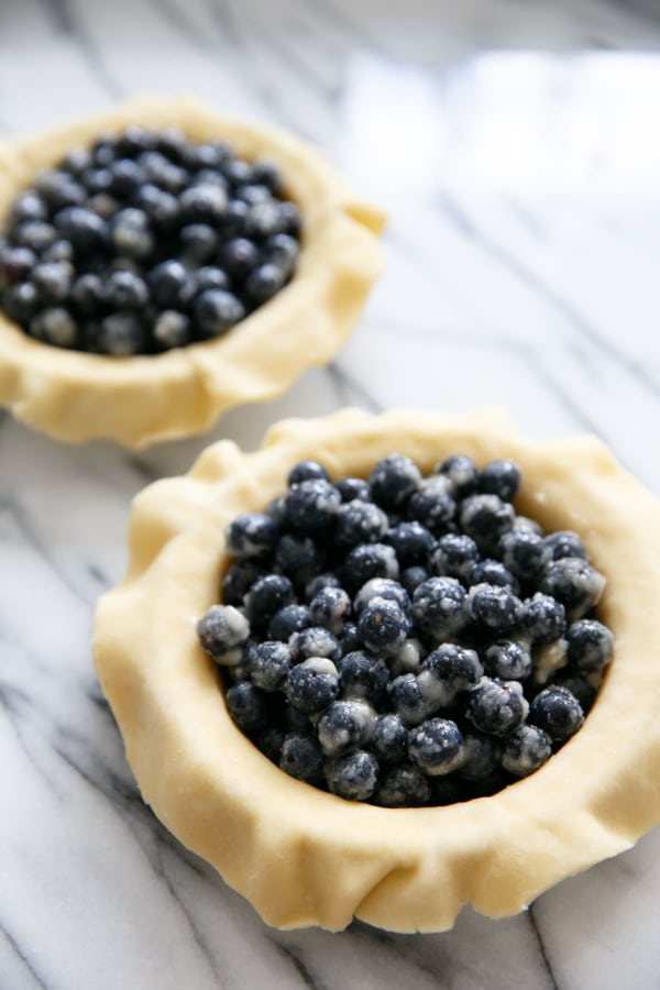 Two unbaked pie shells filled with fresh blueberry filling.