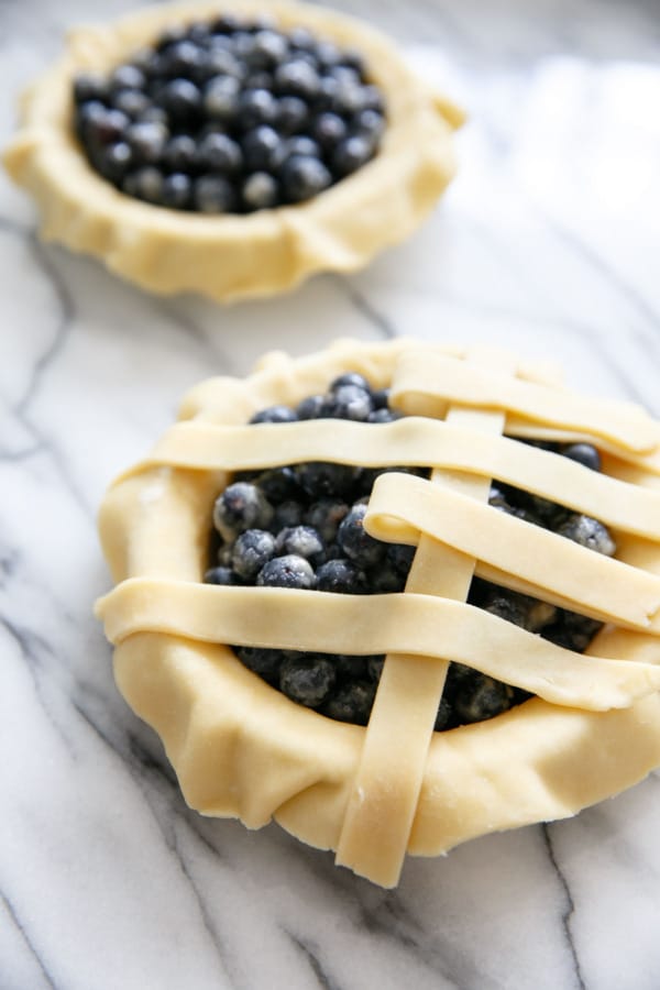 Arranging a lattice top on a mini pie blueberry pie crust.