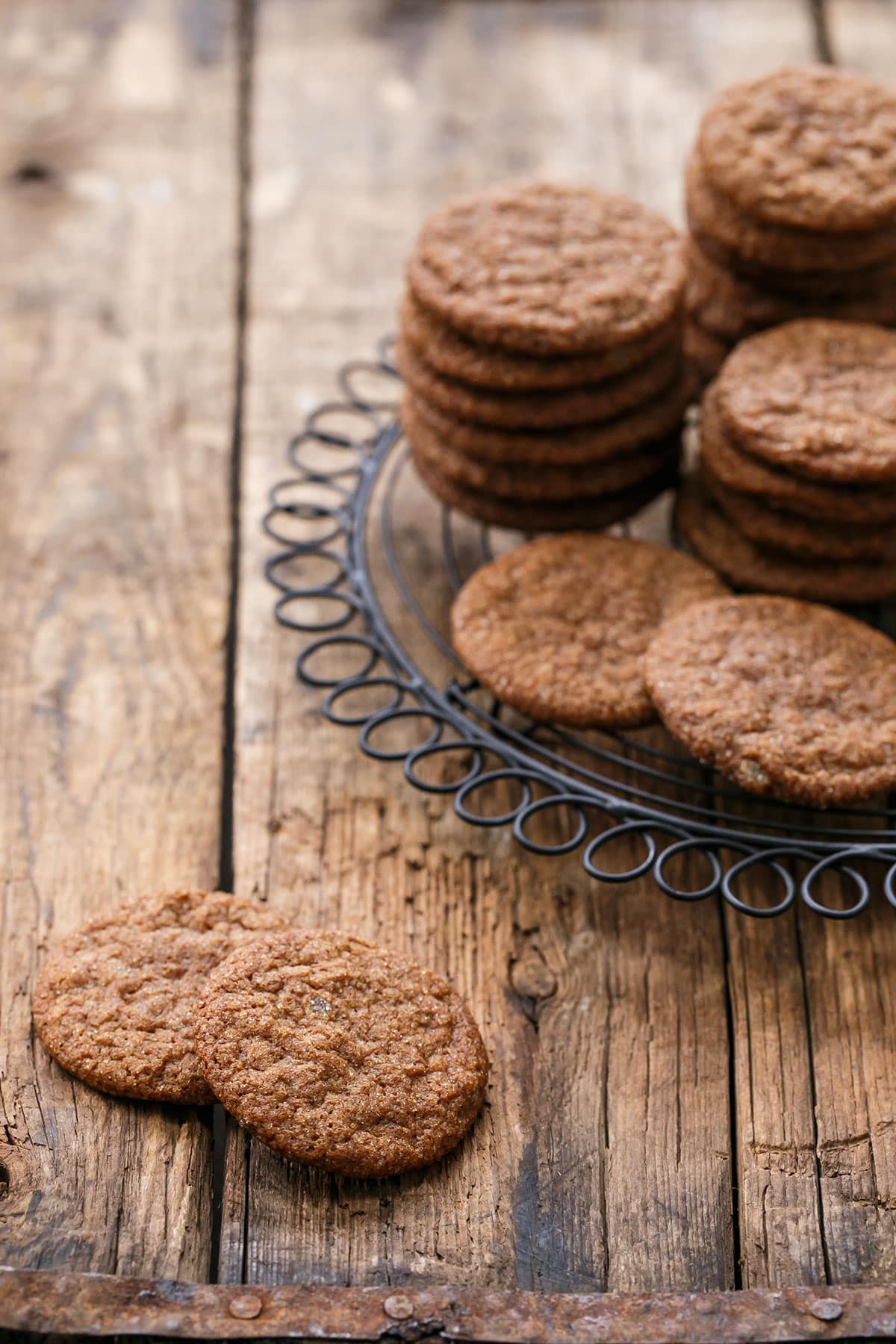 Stacks of Triple Ginger Snap Cookies on a wire rack with a distressed wood background.