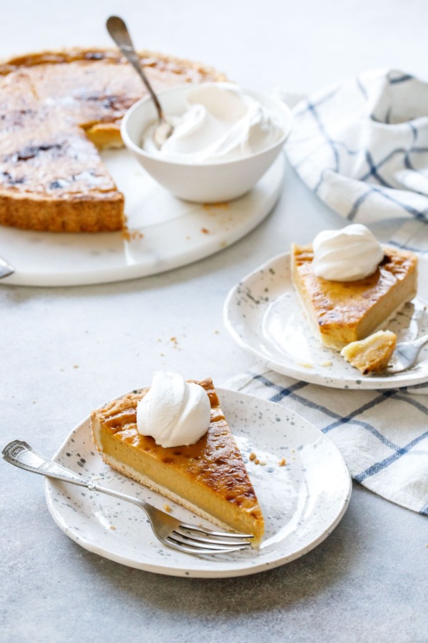 Slice of Pumpkin Custard Tart recipe served with fresh whipped cream