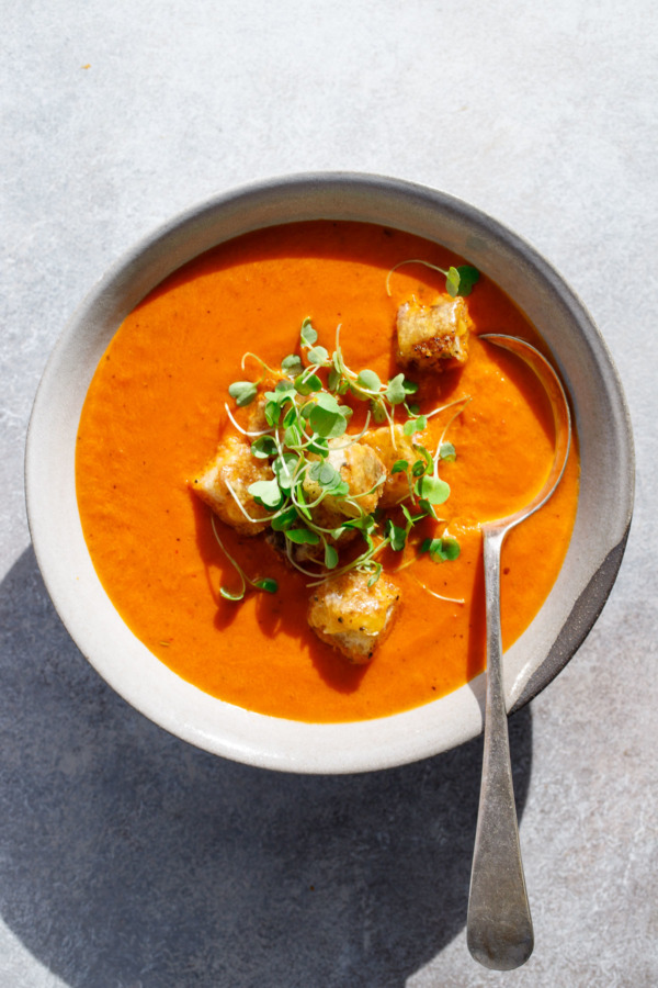 The ultimate comfort food: a bowl of hot tomato soup topped with cheesy croutons and micro basil.