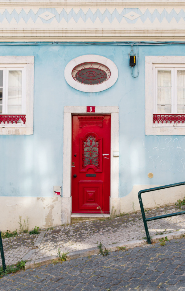 Cute red door on a pastel blue building in Lisbon, Portugal