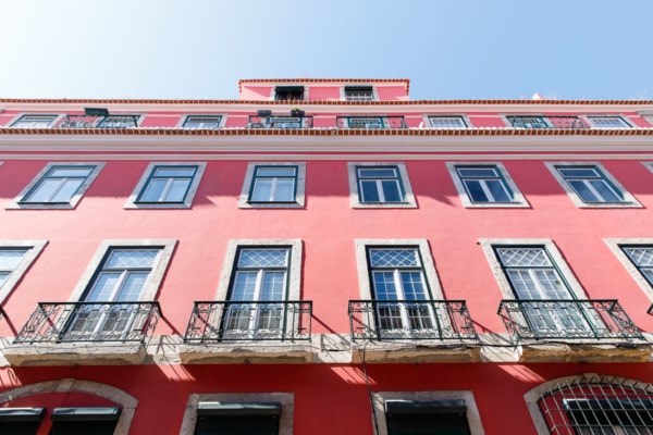 Looking up at a pretty coral pink building and blue sky in Lisbon, Portugal