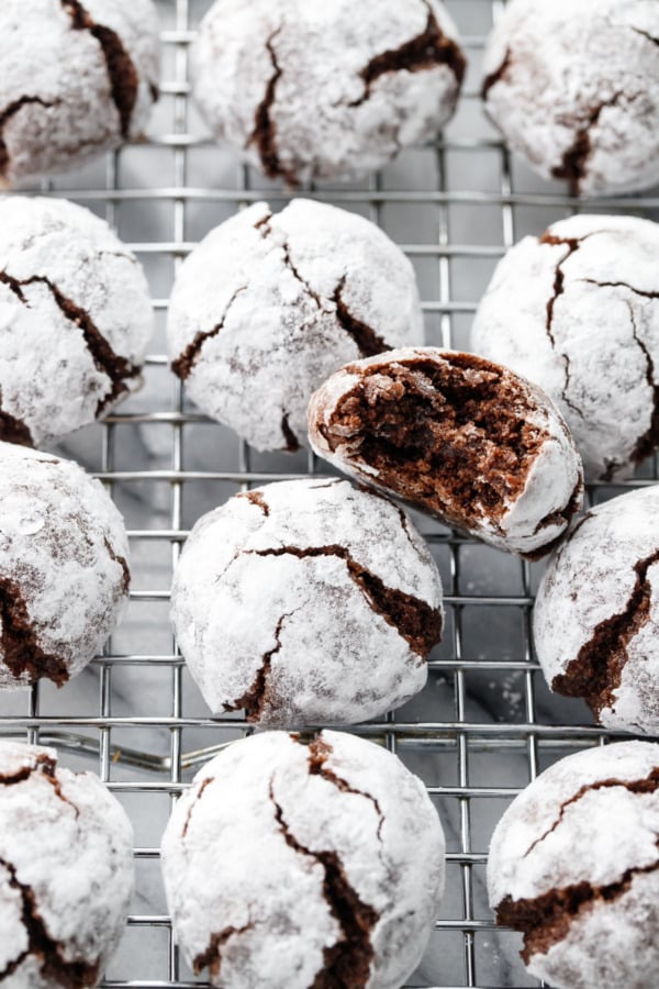 Rows of Chocolate Amaretti Cookies on a wire cooling rack, with one cookie with a bite taken out of it.