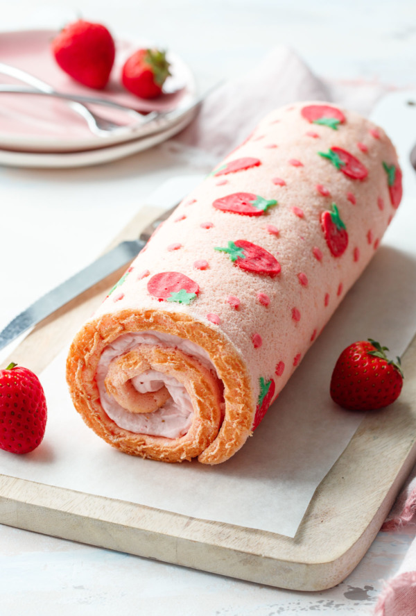 Japanese-style cake roll with a cute cartoon strawberry design on the outside.