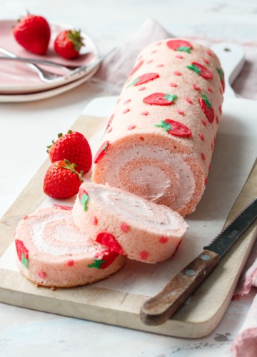 Two slices of a strawberry cake roll, showing the spiral shape and whipped cream filling.