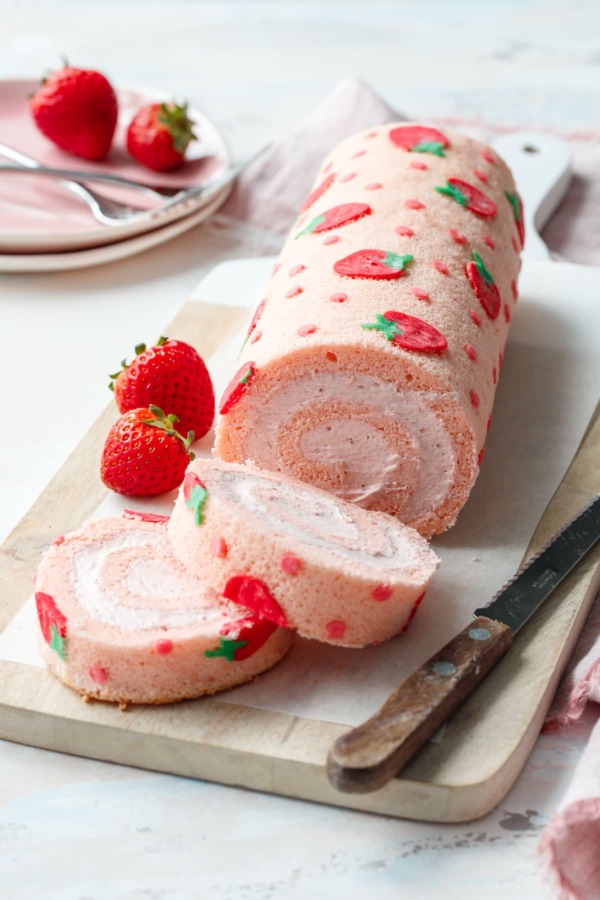 Two slices of a strawberry cake roll, showing the spiral shape and whipped cream filling.