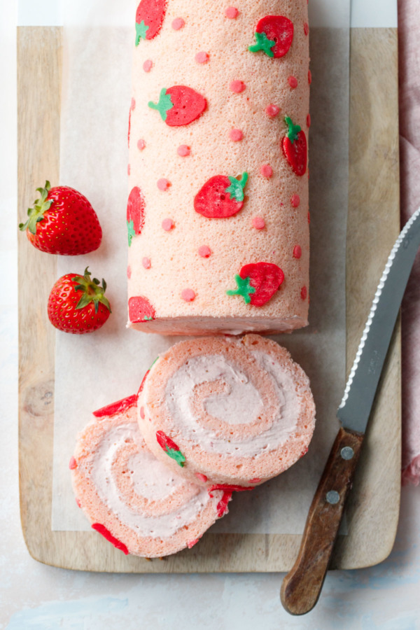 Overhead shot of Spring Strawberry Cake Roll with two slices, and a few strawberries on the side.