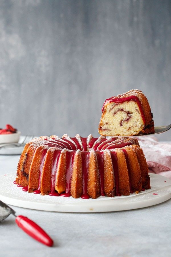 A slice of strawberry hibiscus pound cake being lifted with a cake server.