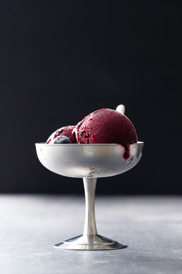 Moody shot of two scoops of Blueberry Ginger Sorbet in a pewter pedestal ice cream cup