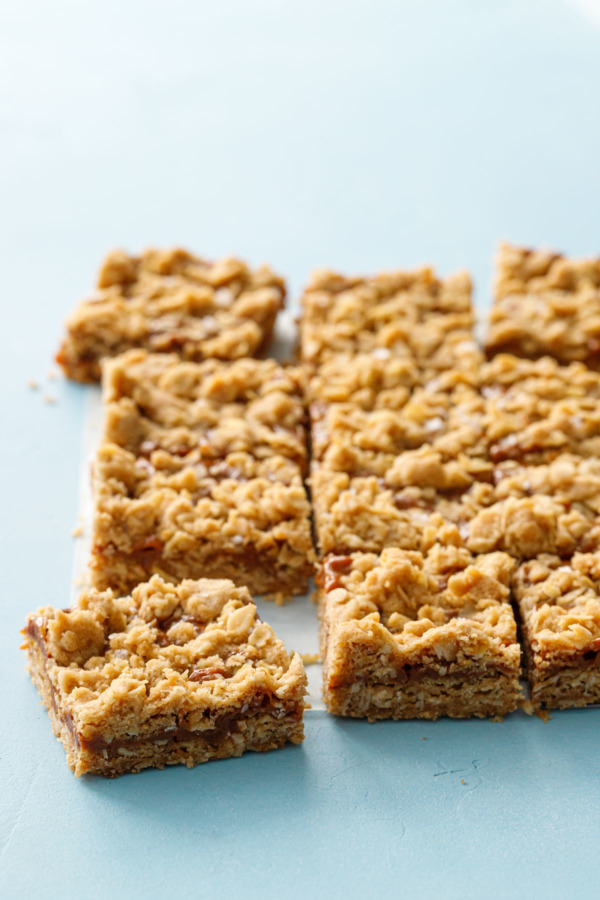 Dulce de Leche Oatmeal Crumb Bars, cut into squares on a light blue background.