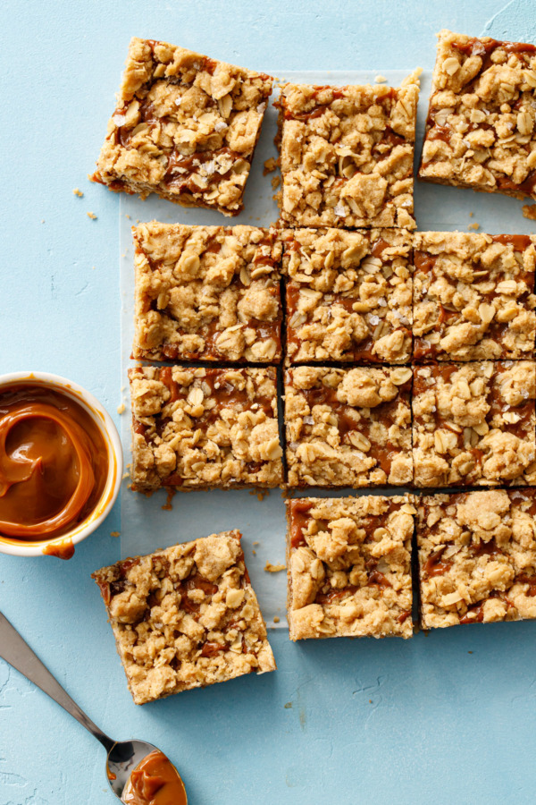 Overhead sot of Dulce de Leche Oatmeal Crumb Bars, cut into squares on a light blue background