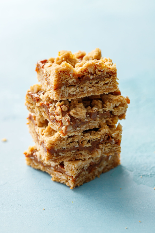 Stack of 4 Dulce de Leche Oatmeal Crumb Bars on a light blue background