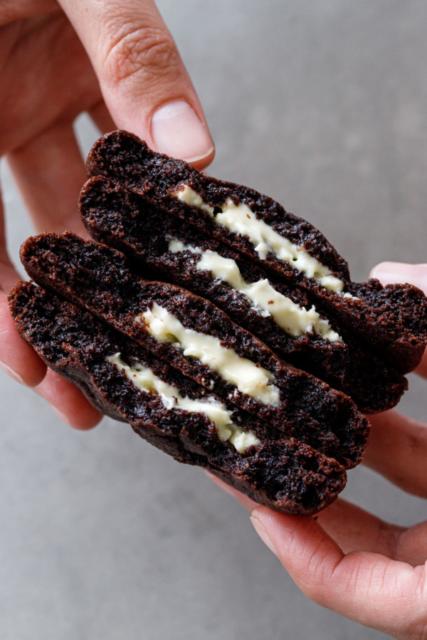 Stack of two chocolate cookies broken in half to reveal the gooey white chocolate centers