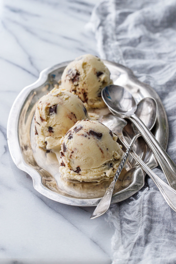 Three scoops of Banana Fudge Chunk Ice Cream on a pewter platter with three spoons on the side.