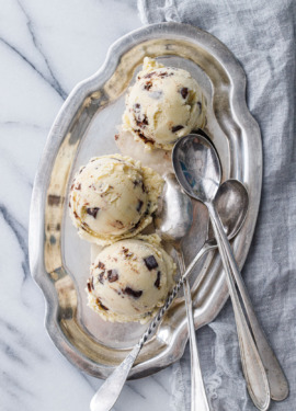 Overhead shot of three scoops of Banana Fudge Chunk Ice Cream on a pewter platter with three spoons on the side.