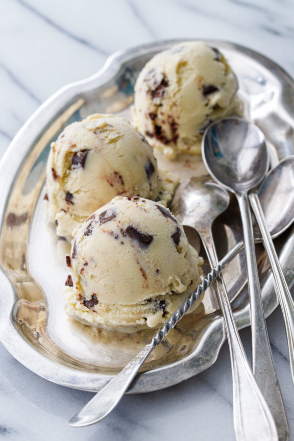 Three scoops of Banana Fudge Chunk Ice Cream on a pewter platter with three spoons on the side.
