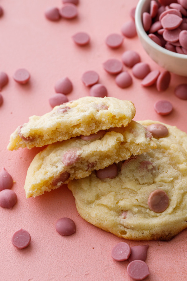Two cookies on a pink background, one broken in half to show the texture of the cookie.