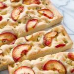 Peach & Fresh Herb Focaccia Bread on a marble background cut into slices