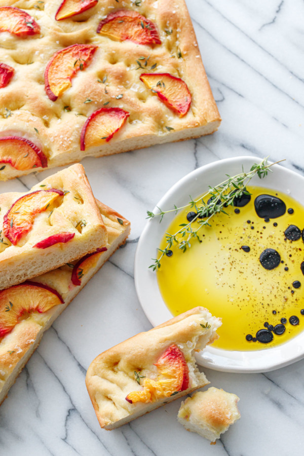 Peach & Thyme Focaccia Bread cut into slices, with a dish of olive oil and balsamic vinegar on the side