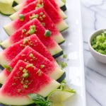 White plate with slices of watermelon, sprinkled with basil lime sugar. Garnished with fresh lime slices and a small bowl of sugar on the side.