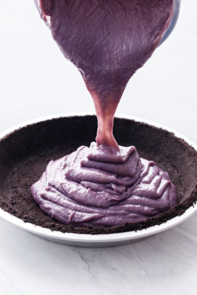 The ube and coconut cream filling being poured into a chocolate cookie crust