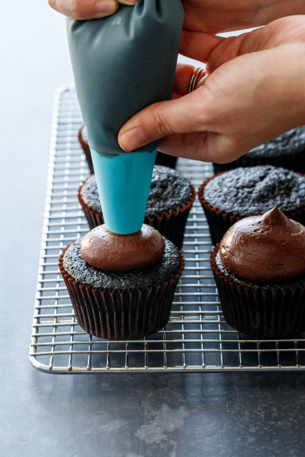 Piping chocolate fudge frosting onto the Ultimate chocolate cupcakes