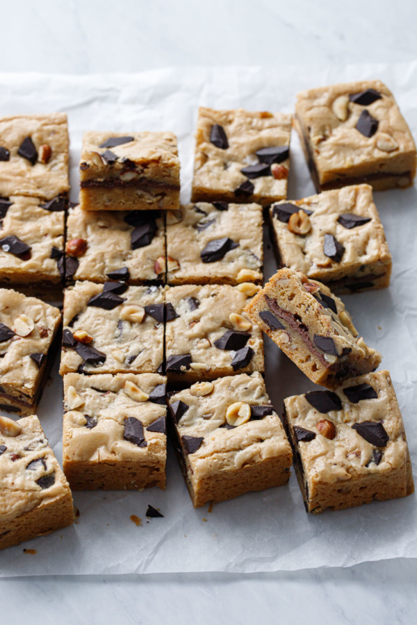 Nutella-Stuffed Brown Butter Blondies cut into squares on parchment paper background