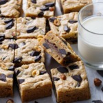 Nutella-Stuffed Brown Butter Blondies cut into squares with a glass of milk on the side.