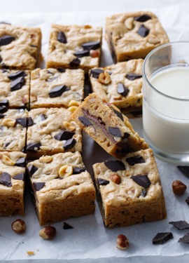 Nutella-Stuffed Brown Butter Blondies cut into squares with a glass of milk on the side.