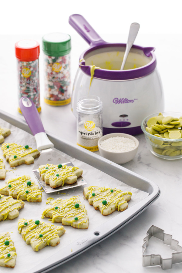 Cookie sheet with pistachio cutout cookies and the various Wilton tools used to make and decorate them.