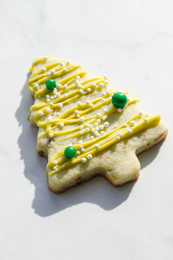 Closeup of a Christmas tree pistachio cookie with a harsh shadow.