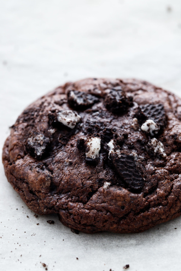 Extreme close up of a baked chocolate cookies 'n cream cookie, topped with pieces of crushed up oreo cookies