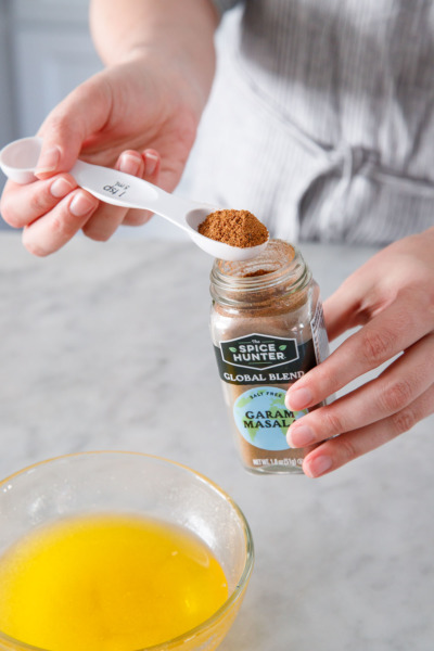 Measuring the garam masala spice blend into the melted clarified butter.