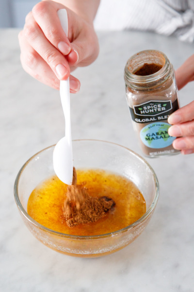 Measuring the garam masala spice blend into the melted clarified butter.