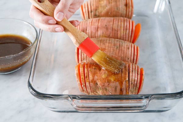 Brushing the sliced sweet potatoes with spice butter mixture.