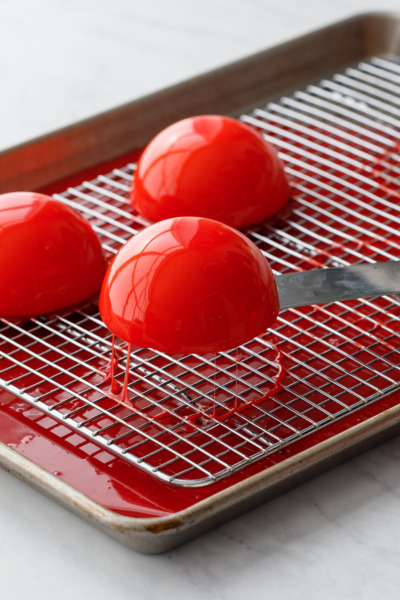 How-To Entremet Cake Process: Use a wet offset spatula to lift the cake off of the wire rack and clean up any drips.