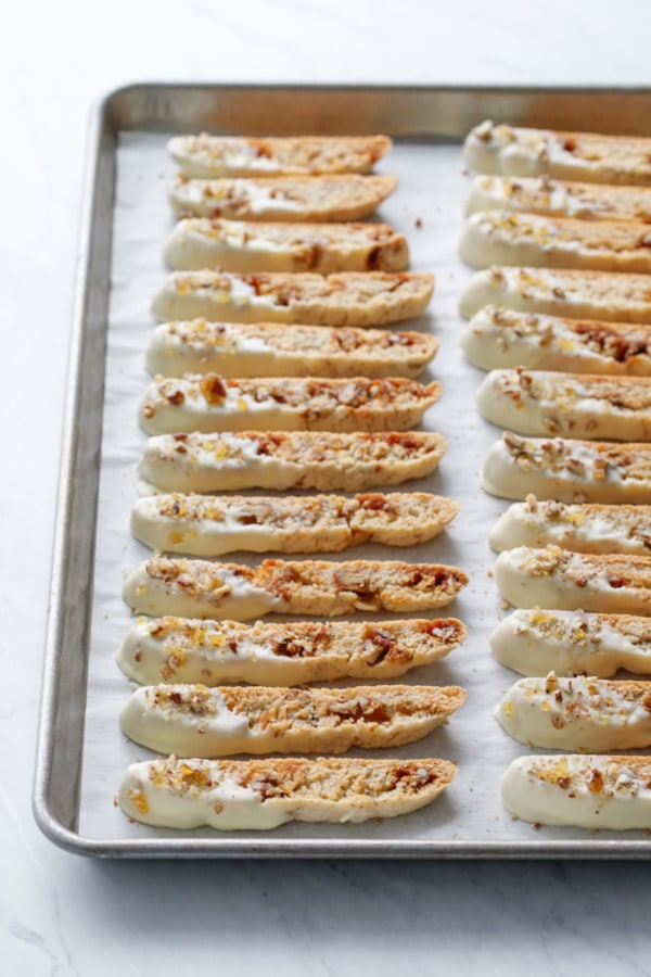 Rows of white-chocolate dipped biscotti neatly lined up on a baking sheet