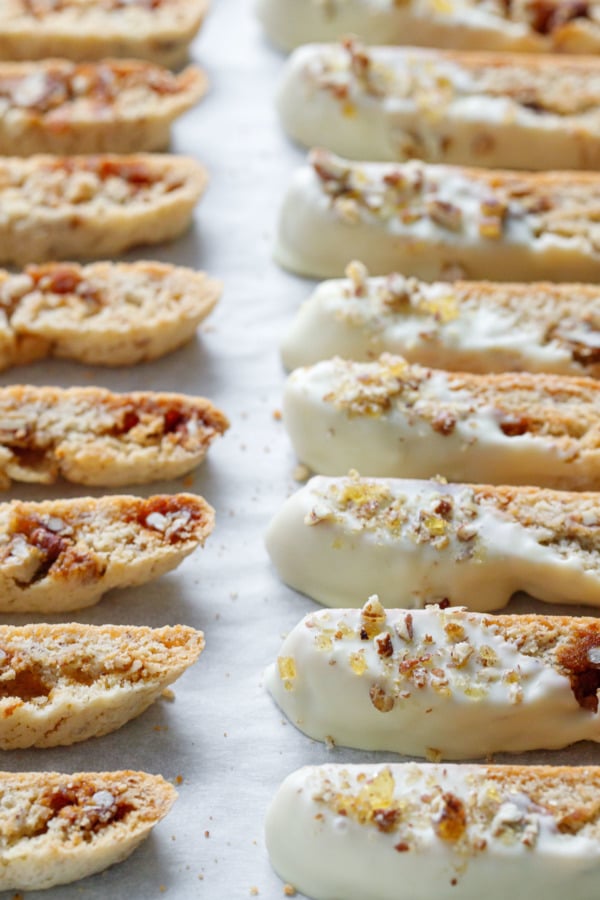 Closeup of white-chocolate dipped biscotti cookies on a parchment-lined baking sheet