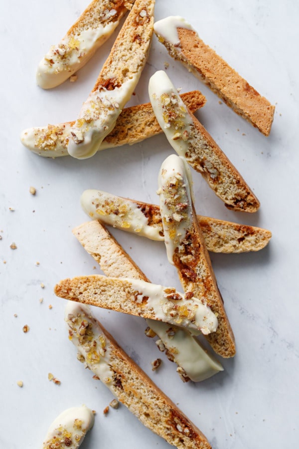 White chocolate dipped biscotti cookies scattered and stacked on a marble background