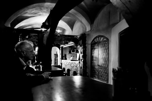 Black and white, old man sitting at the table inside an historic restaurant in Ljubljana, Slovenia