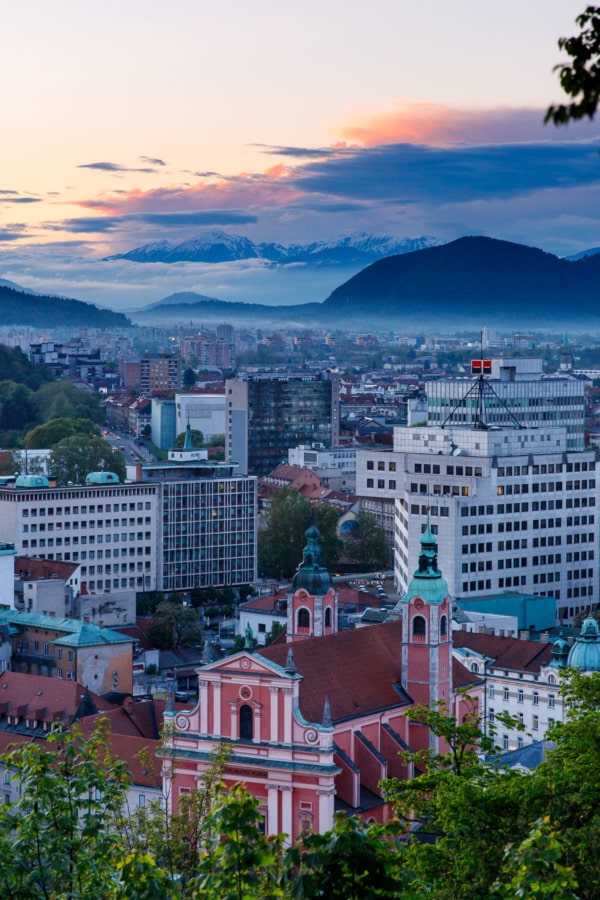 Sunset in Ljubljana, Slovenia, looking out over the city and the snow-covered mountains in the background.