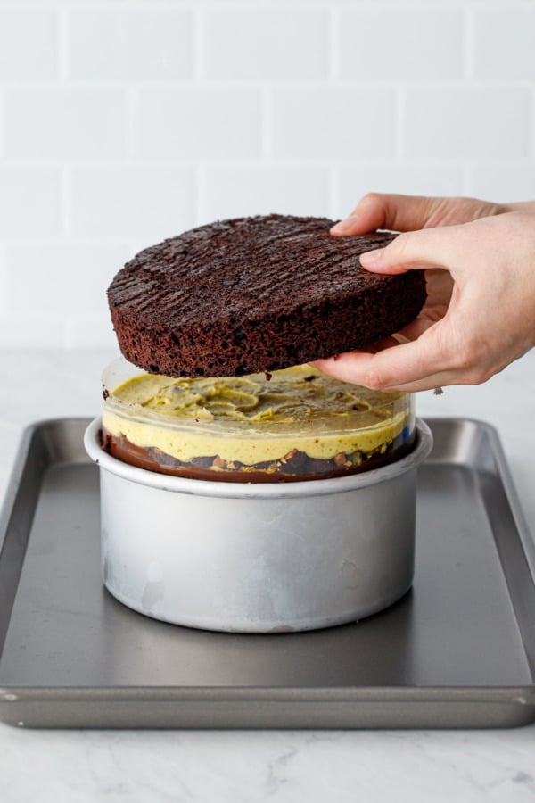 Assembling a naked layer cake: adding the final l ayer of chocolate cake.