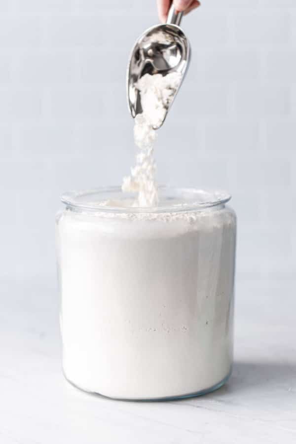 Scooping flour out of a glass canister