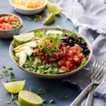 Turkey Taco Bowls with Cilantro Rice on a dark blue background with bowls of salsa and cheese and slices of lime scattered around.